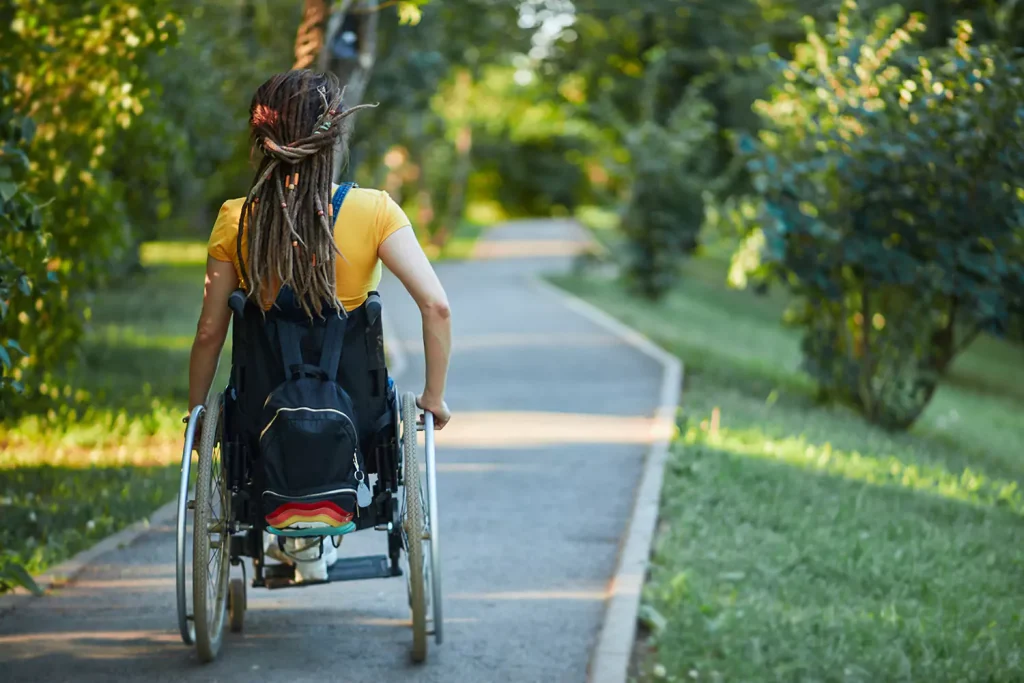 Disabled woman in wheelchair on path in park