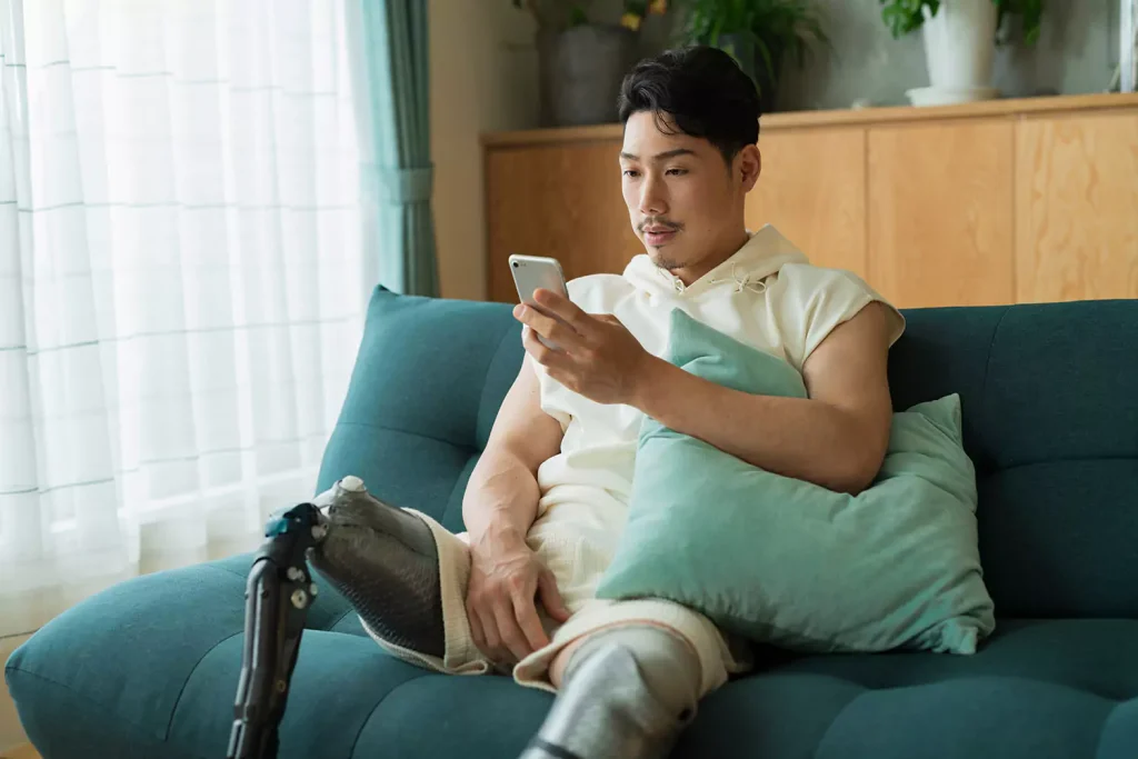 Disabled man sitting on couch using mobile phone